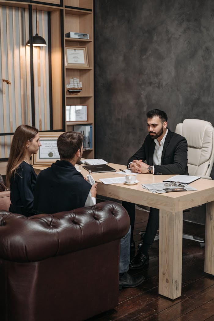 Mastering the First Impression: Your intriguing post title goes here A professional business meeting with three people discussing documents in an office setting.